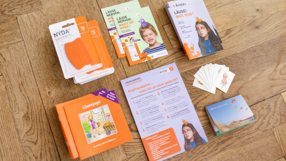 NYDA-Servicepaket mit Broschüren, Karten, Faltblättern und Informationsmaterial auf einem Holzboden.