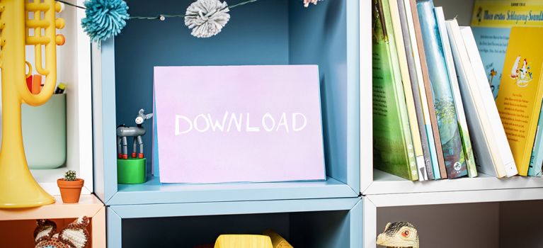 Lila Karte mit der Aufschrift „DOWNLOAD“ in einem Regal, umgeben von Spielzeug und Büchern.