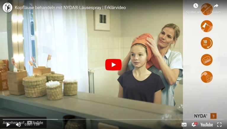 Frau wickelt ein Handtuch um den Kopf eines Mädchens im Badezimmer. Produkte zur Behandlung von Kopfläusen sichtbar.