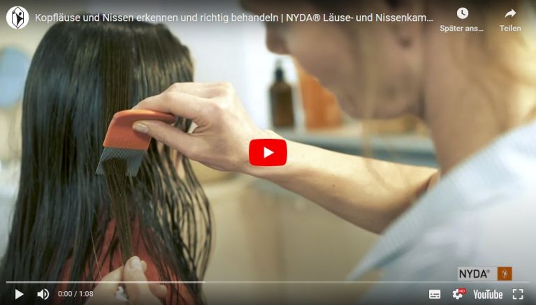 NYDA® Läuse- und Nissenkamm wird durch eine Hand in feuchtem Haar benutzt. Hintergrund mit Pflegeprodukten auf Holzablage.