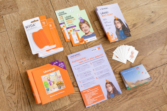 NYDA-Servicepaket mit Broschüren, Karten, Faltblättern und Informationsmaterial auf einem Holzboden.