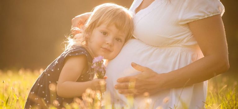 Läuse in der Schwangerschaft: Kind legt den Kopf auf den Bauch der schwangeren Mutter.