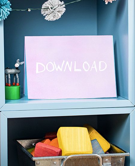 Ein Regal mit einem Schild, auf dem in weißen Buchstaben „Download“ steht. Darunter befindet sich eine Kiste mit bunten Holzbausteinen.