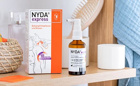 Packshot NYDA® express Läusespray mit Verpackung im Badezimmer zur schnellen Behandlung von Kopfläusen.