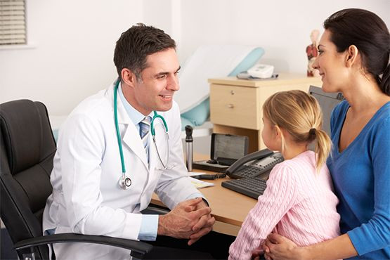 Lausbefall bei Kindern – Therapie mit NYDA® schnell einleiten. Arzt im Gespräch mit Mutter und Tochter in einer Praxis, bespricht Behandlungsoptionen.